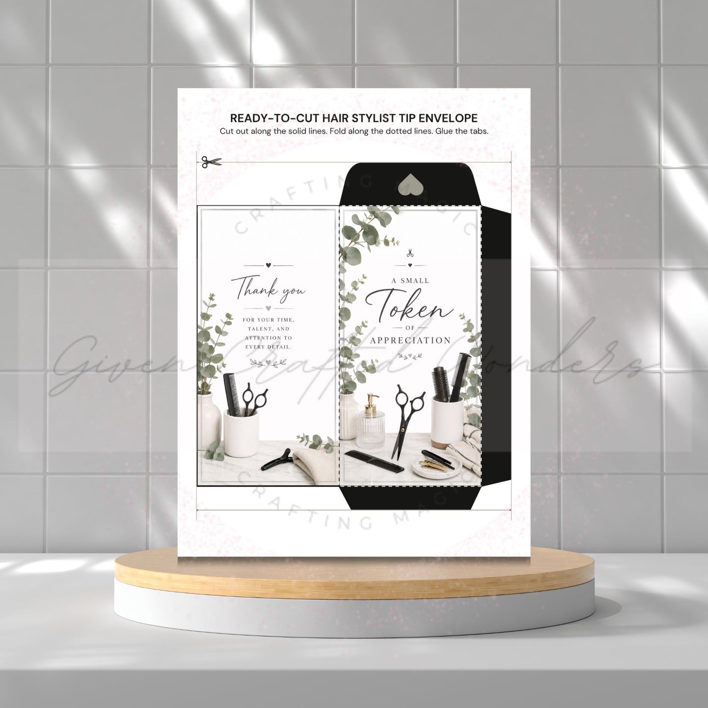 A printed hair stylist tip envelope card displayed upright on a round pedestal against a light gray tiled wall. The card shows a black-and-white envelope design with botanical leaf accents and small salon tools, plus text including 'READY-TO-CUT HAIR STYLIST TIP ENVELOPE' and 'A Small Token of APPRECIATION'.