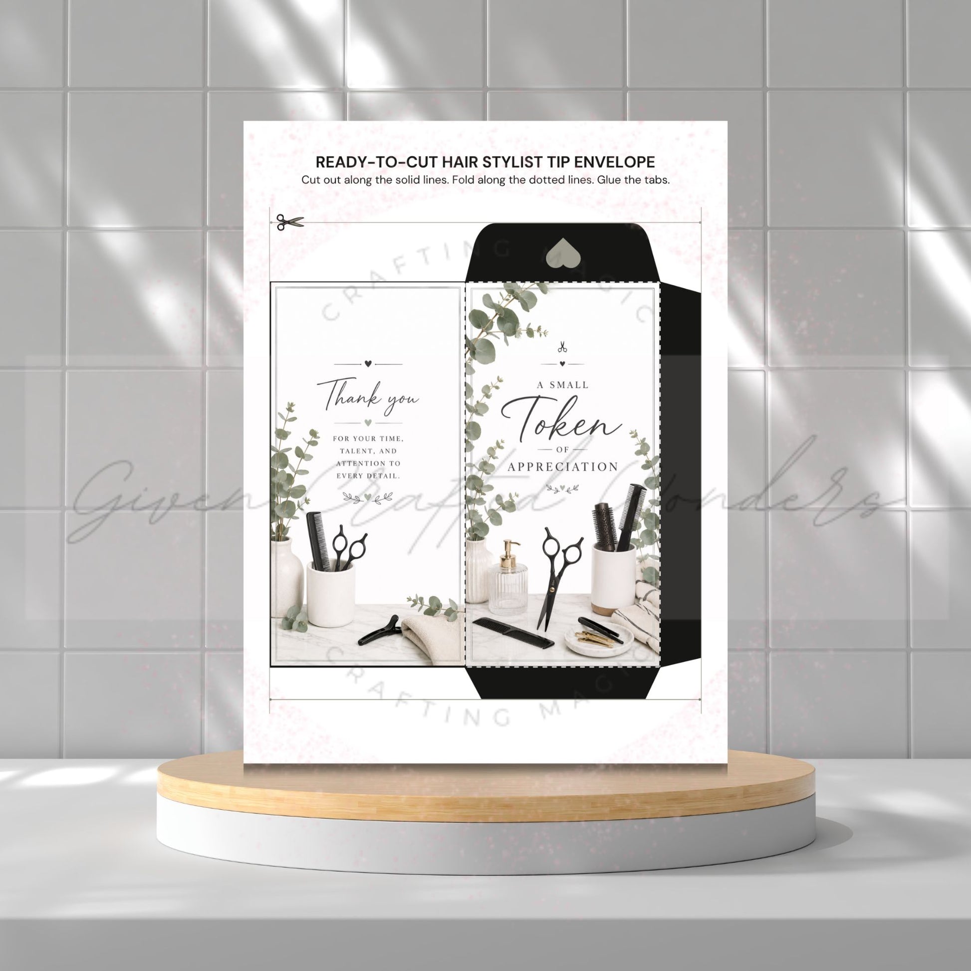 A printed hair stylist tip envelope card displayed upright on a round pedestal against a light gray tiled wall. The card shows a black-and-white envelope design with botanical leaf accents and small salon tools, plus text including 'READY-TO-CUT HAIR STYLIST TIP ENVELOPE' and 'A Small Token of APPRECIATION'.