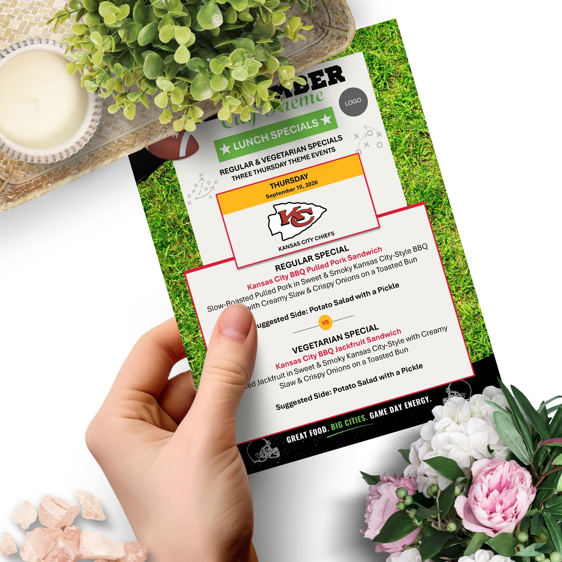 A hand holds a printed restaurant menu card featuring 'Roder Home' lunch specials, with a white background and decorative plants and flowers around it.