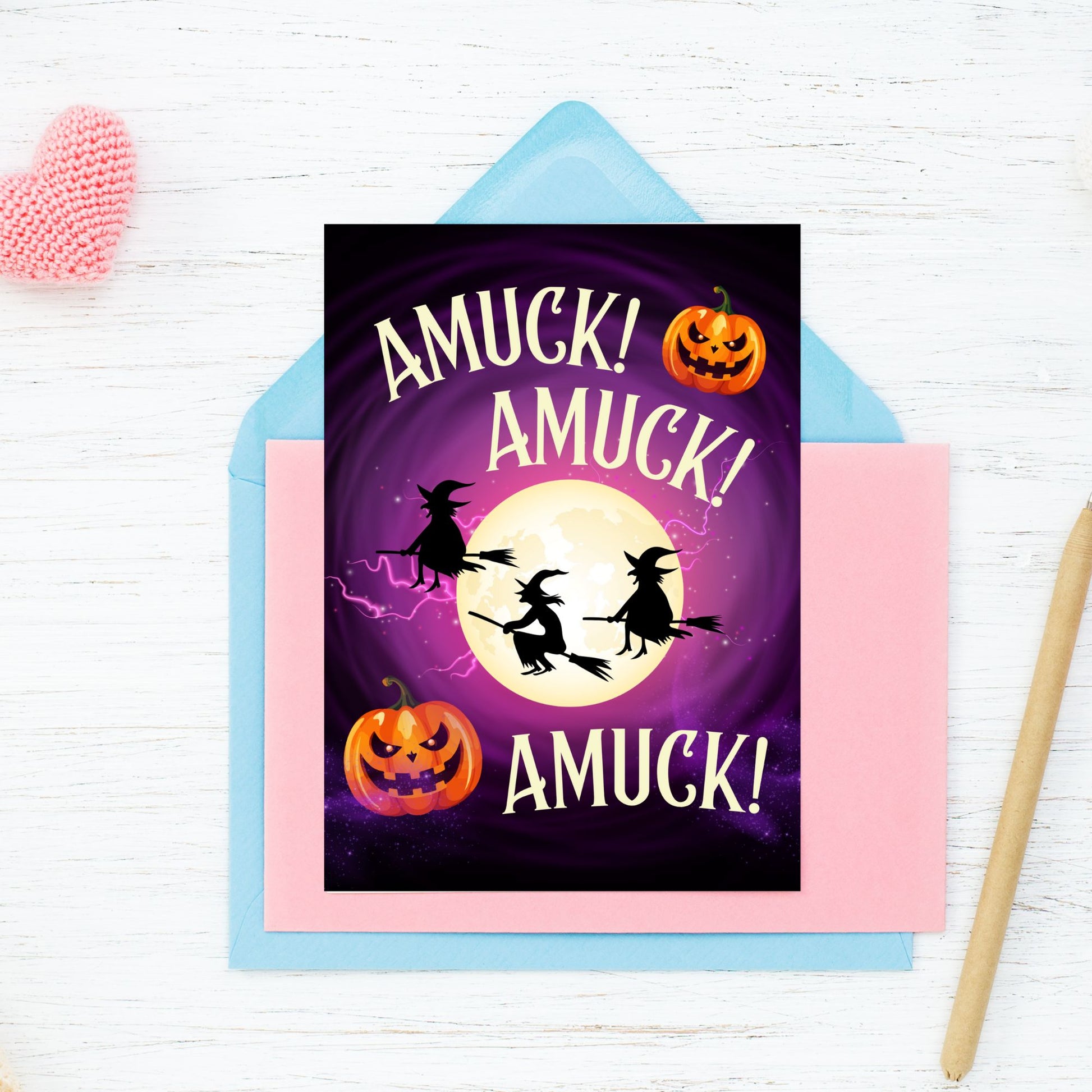 Halloween-themed card with witches and pumpkins on a purple background, placed on a white surface.