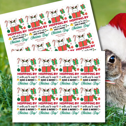 Christmas gift tags featuring a cute bunny peeking out of a red gift box with festive elements like candy canes, ornaments, and presents. The tag reads 'Hopping By with Joy to Say Have a Merry Christmas Day!'