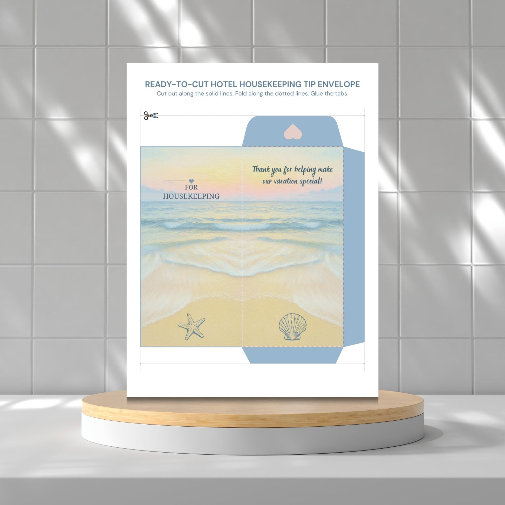 A printed housekeeping tip envelope template or packaging insert displayed upright on a round wooden pedestal against a light gray tiled wall. The insert has beach-themed artwork with blue water, pale yellow sand, a starfish, a shell, and text including 'thank you for helping make our vacation special!' and 'FOR HOUSEKEEPING'.