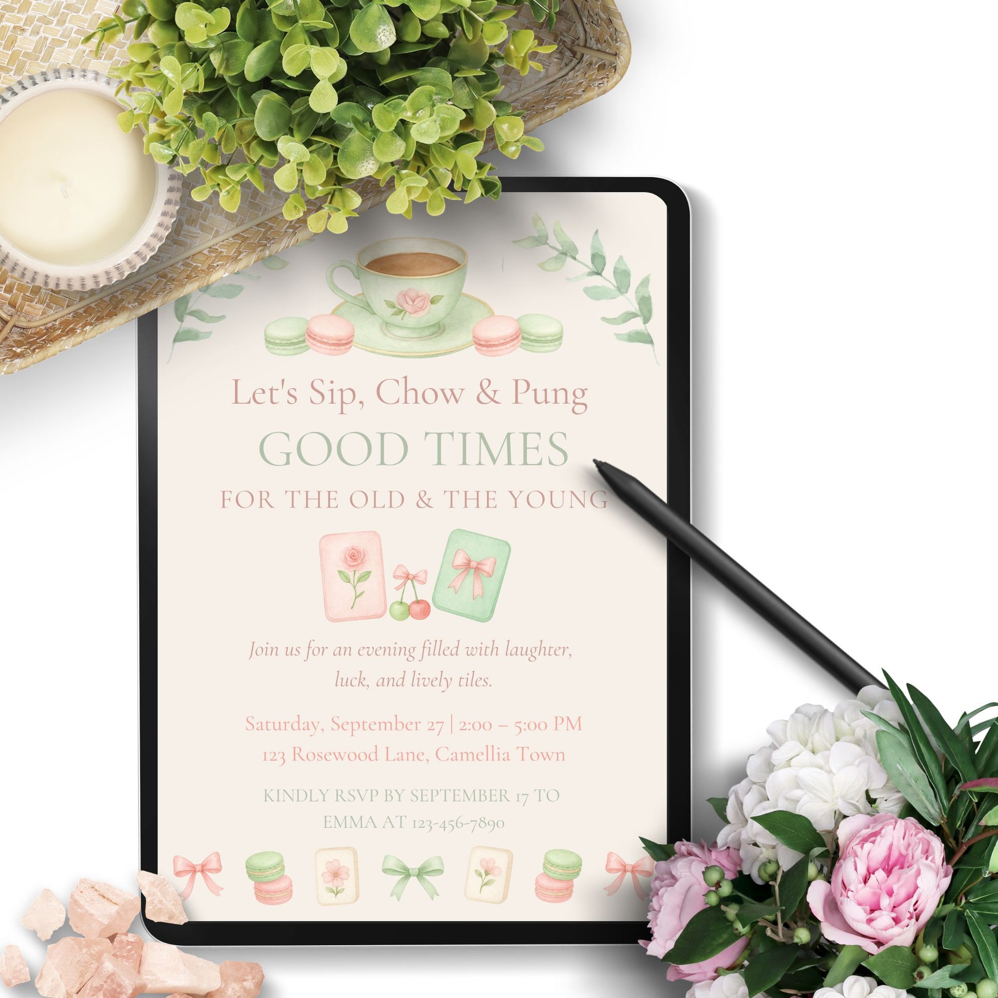 Invitation card with tea cup design on a tablet surrounded by flowers and a teacup.