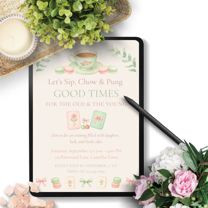 Invitation card with tea cup design on a tablet surrounded by flowers and a teacup.