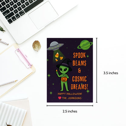 Halloween-themed card with alien design and text, placed on a desk with a laptop.