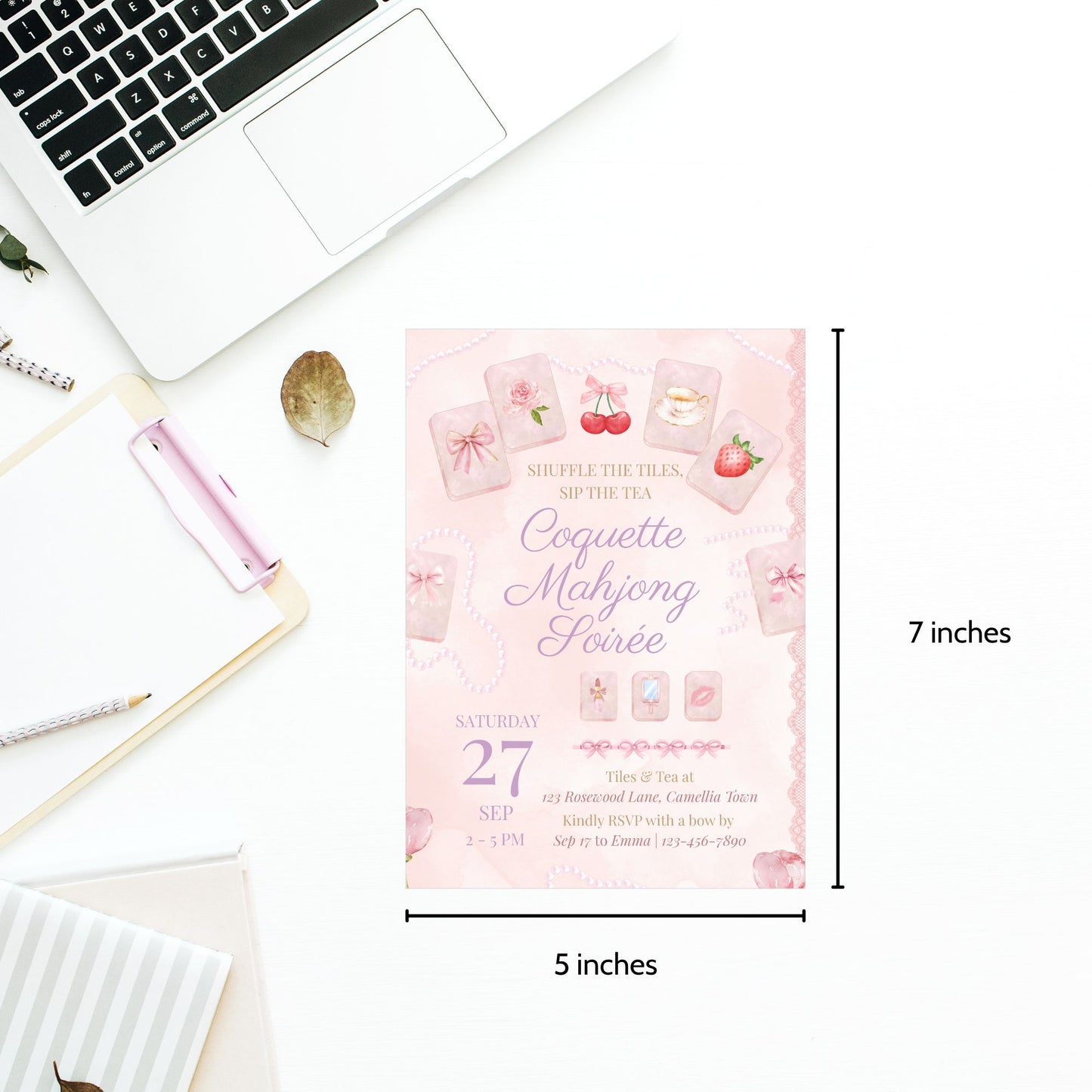 Pink card with text and graphics on a desk with a laptop and stationery items.