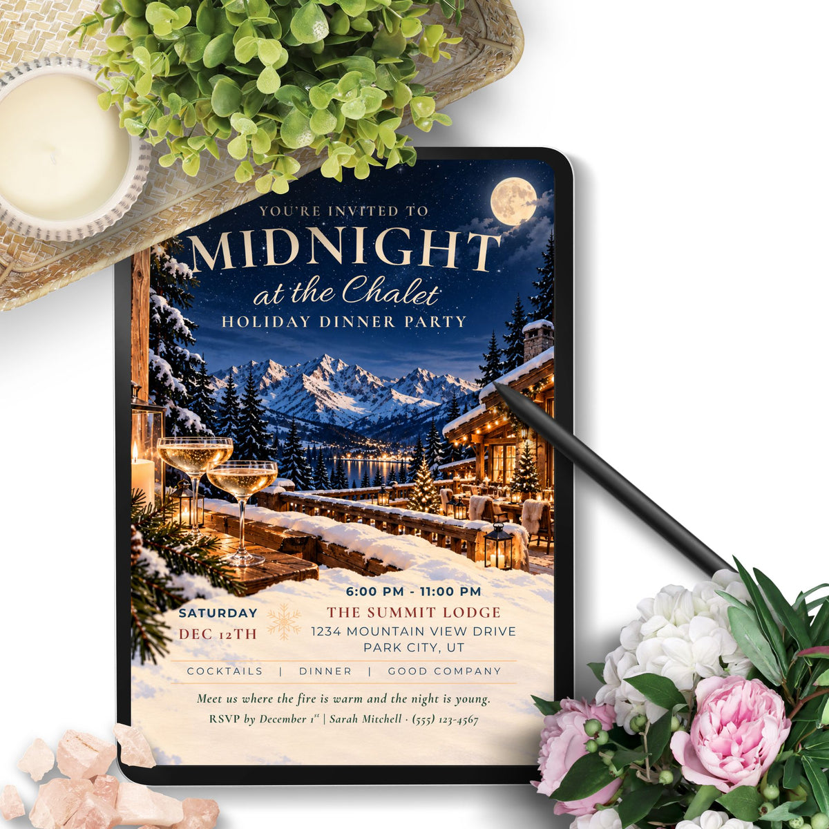 A digital holiday dinner party invitation displayed on a tablet screen, surrounded by decorative flowers, greenery, and a pen on a white background.