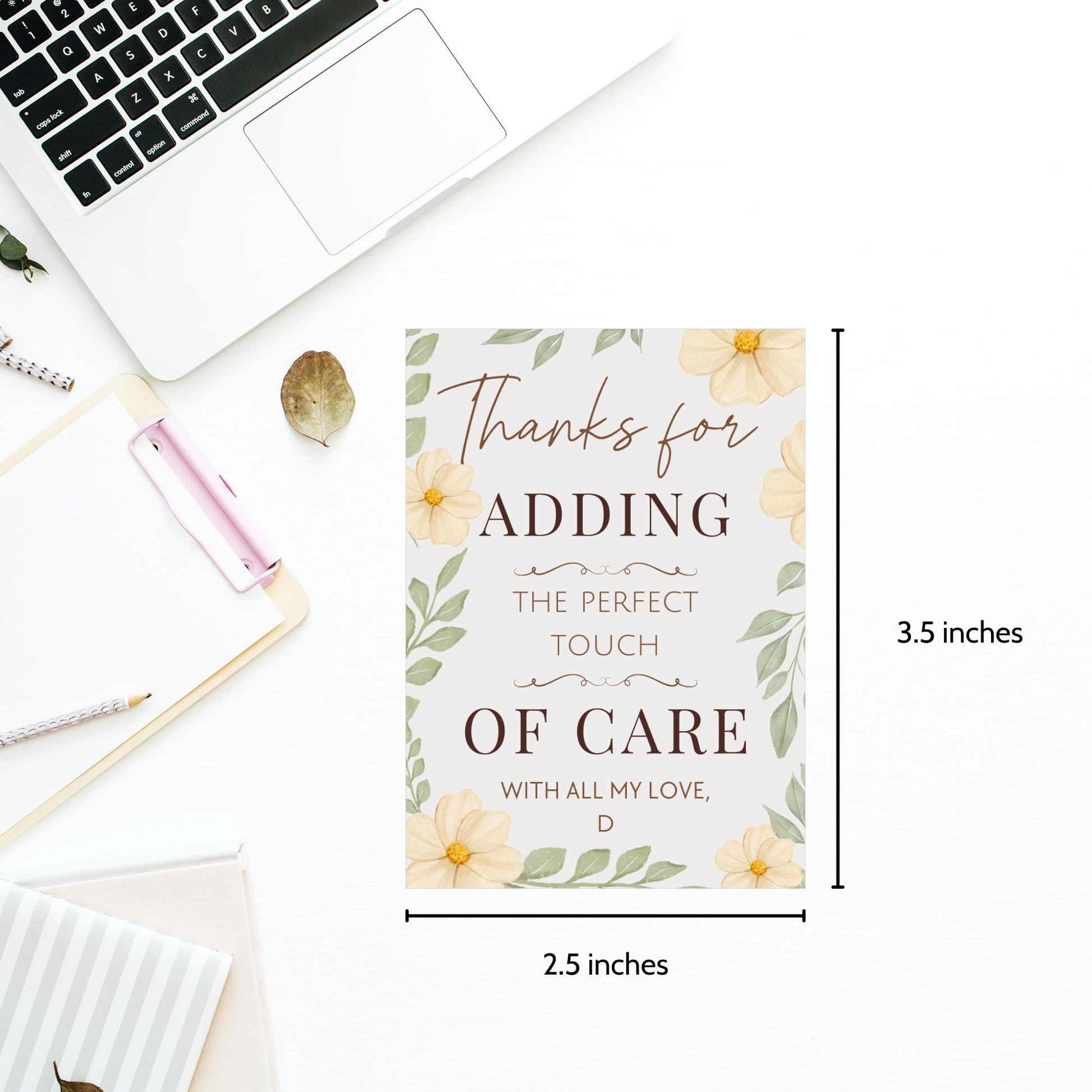 Card with floral design and text on a desk with laptop and stationery items.