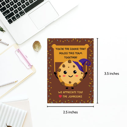 Halloween-themed printable gift tags featuring a cute cookie character in a witch's hat with a sign reading, "You're the cookie that holds this team together!" Tags are 2.5 x 3.5 inches, laid out 8 per sheet on a standard 8.5 x 11-inch page. Includes a printable PDF and a PDF with a link to an editable Canva template.