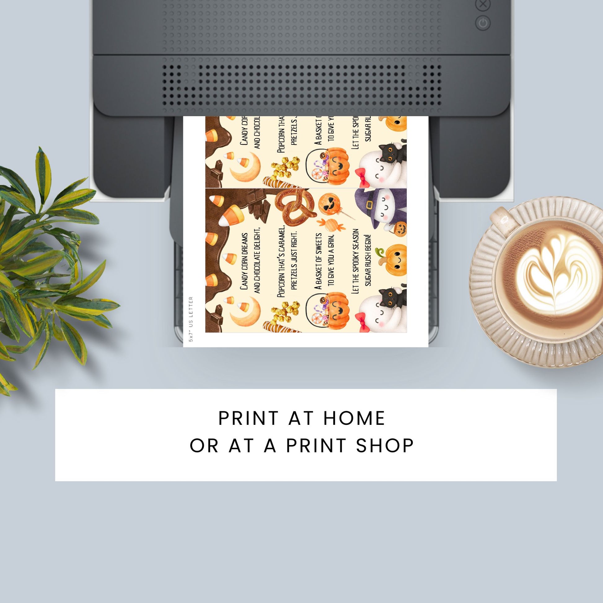 Printer with a printed sheet featuring Halloween-themed designs on a light blue surface with a plant and coffee cup.