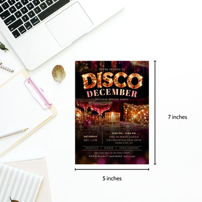 A 5x7 inch disco-themed birthday party invitation card shown on a white desk flat-lay with a laptop, notebook, and pen. The card features a dark background with warm orange and gold glittery text reading 'DISCO DECEMBER' and a blurred dancefloor scene.