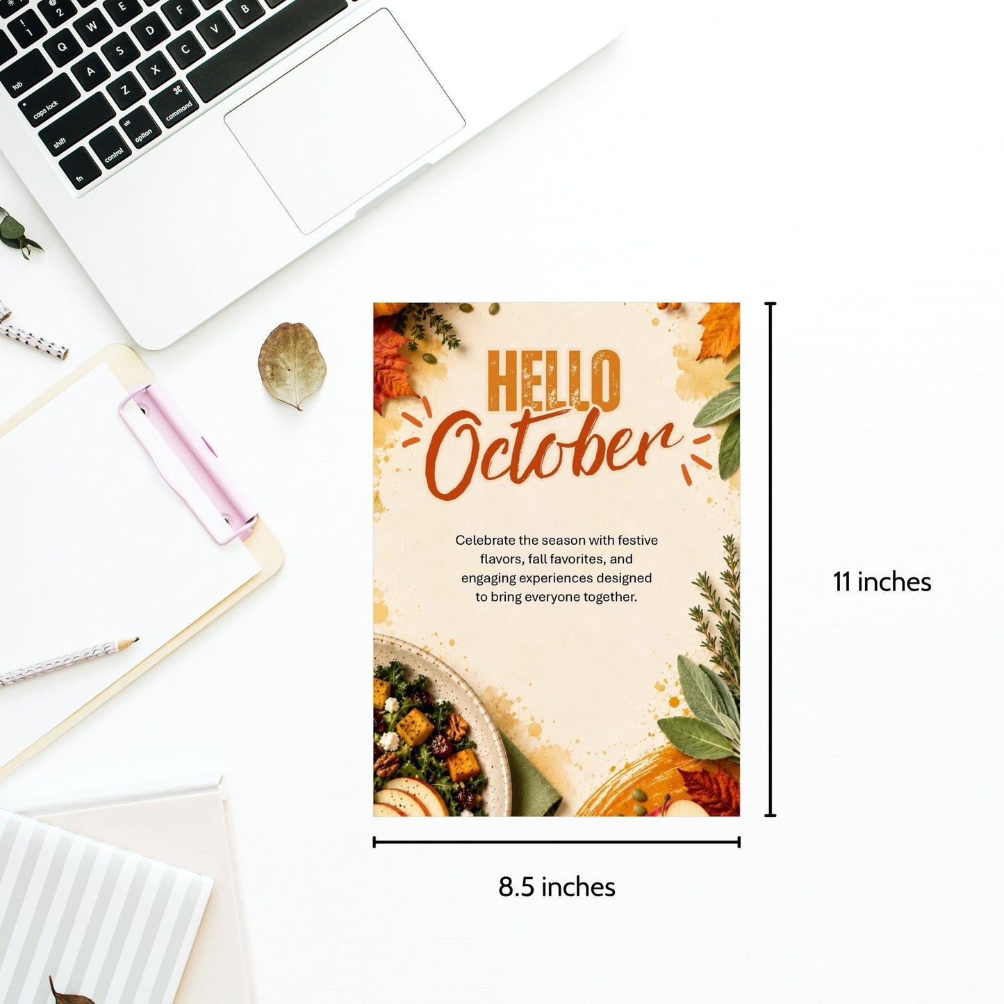 A flat-lay mockup of a vertical autumn-themed 'Hello October' poster on a white desk with a laptop, notebook, and pen. The poster features a warm beige background with orange text, green leaves, and food illustrations, with dimension lines indicating 11 inches tall by 8.