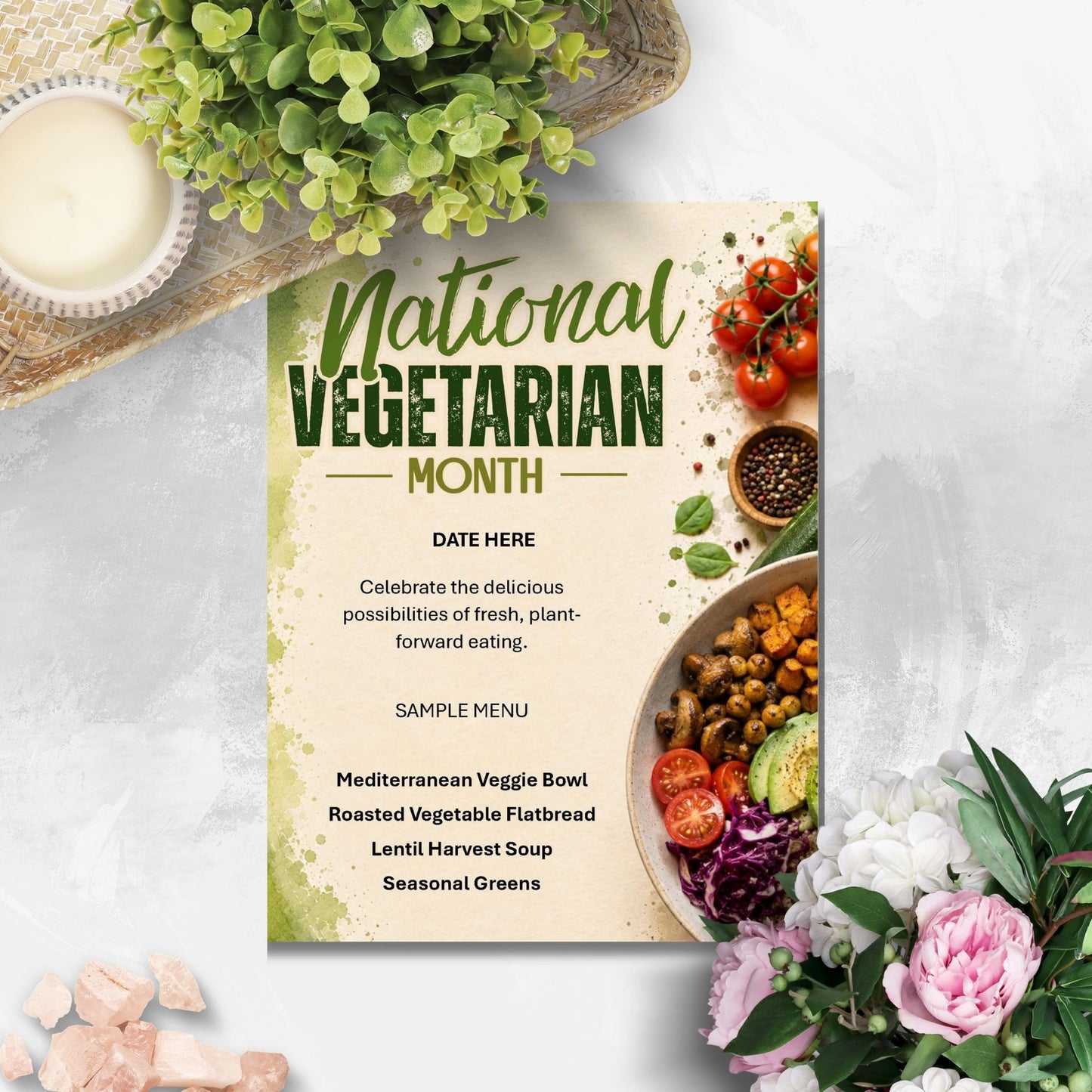 A decorative printed card reading 'National Vegetarian Month' with sample menu items and food photography, styled on a light textured surface with flowers, greenery, and small stones around it.