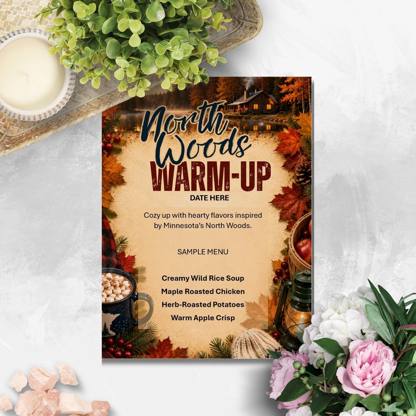 A fall-themed restaurant or event menu card titled 'North Woods Warm-Up' styled in a flat-lay arrangement with a candle, greenery, and flowers on a light textured surface.