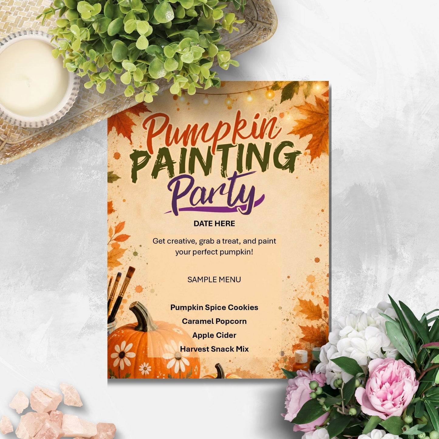 A fall-themed 'Pumpkin Painting Party' invitation card styled in a flat-lay arrangement with a candle, green leaves, and pink flowers on a light gray textured background.