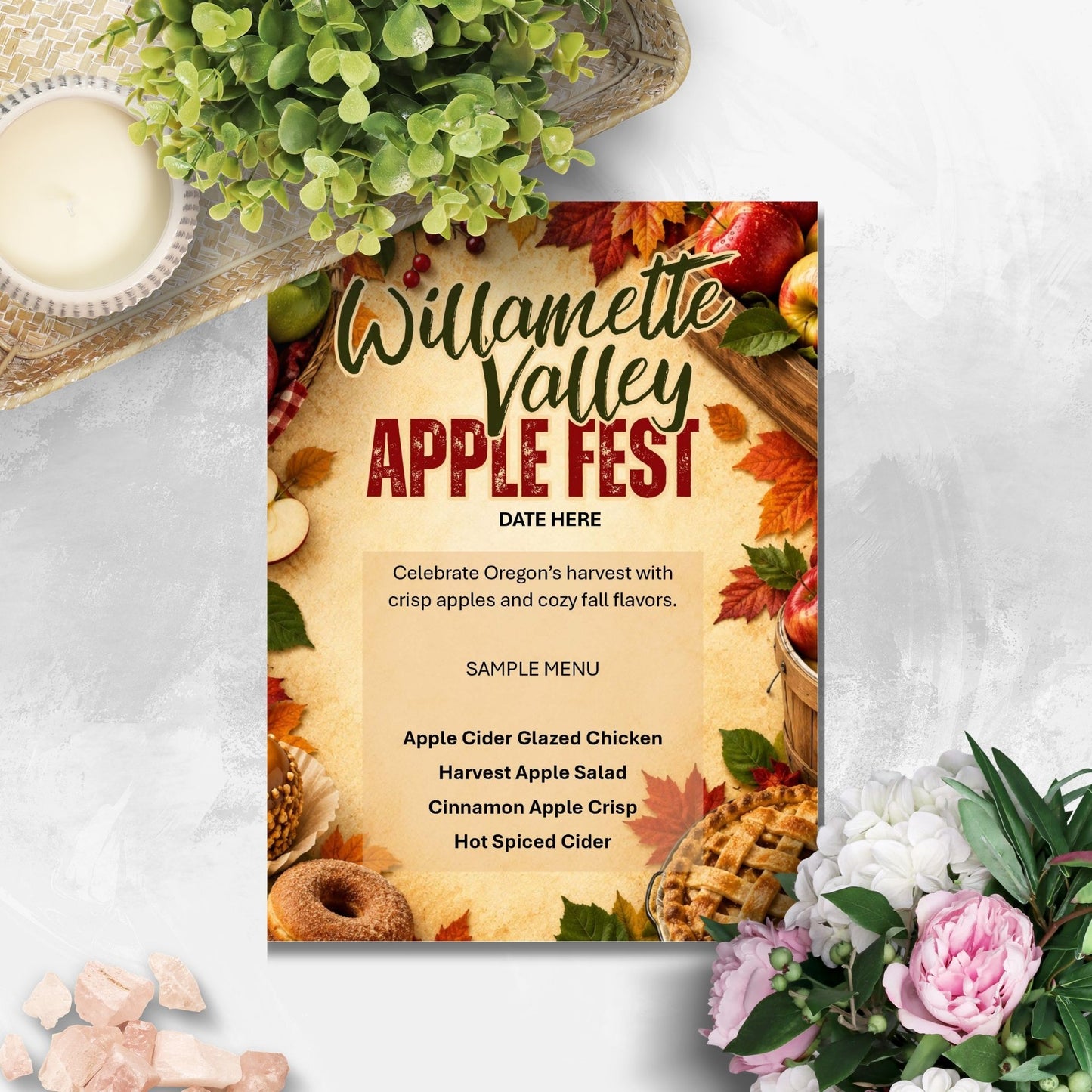 A fall-themed 'Willamette Valley Apple Fest' flyer or menu card displayed on a light gray textured surface with decorative props including a candle, greenery, and flowers.